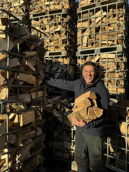 Koen voor een stapel brandhout